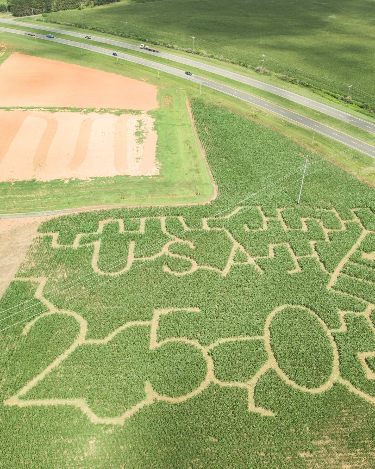 Close aerial view of the USA lettering and nearby trails in the Deer Run Farm corn maze, with fields and the highway beyond